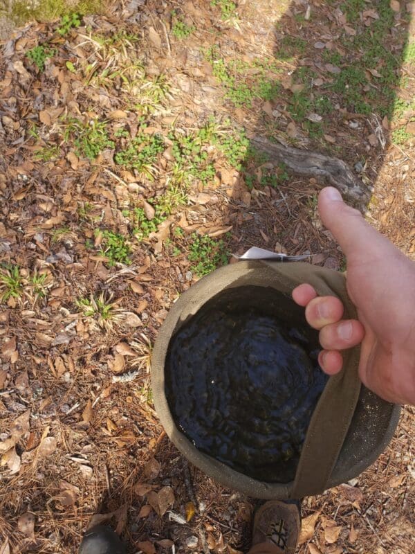 A person holding a Large Canvas Collapsible Water Bucket (ROTHCO).