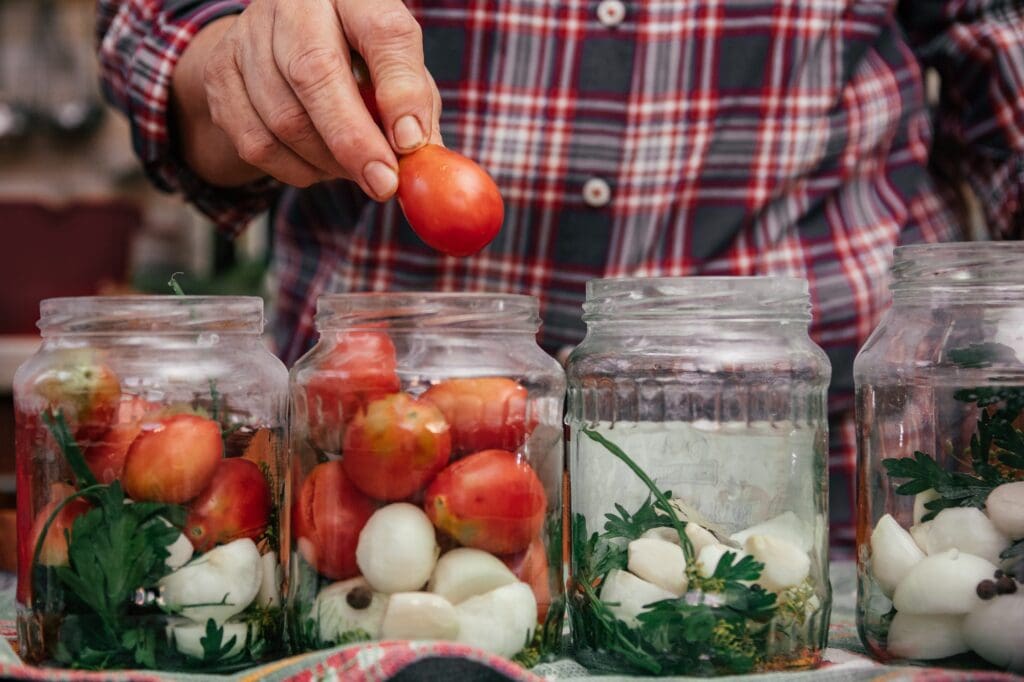 Canning process, female hand preparing tomatoes to preservation into glass jars