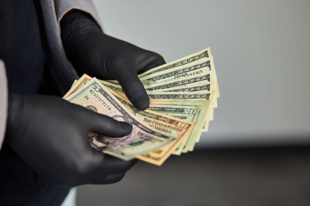 Man holding money dollars in hand in black medical gloves.