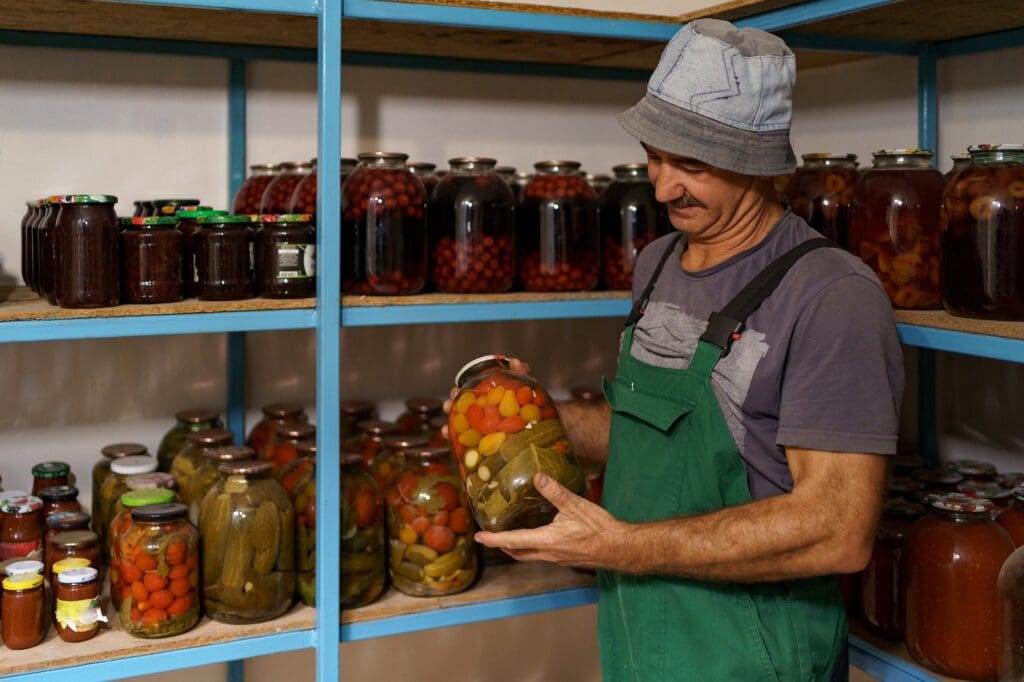 Home made canned veggies. Healthy food. Man looking at his harvested canned tomatoes and cucumbers