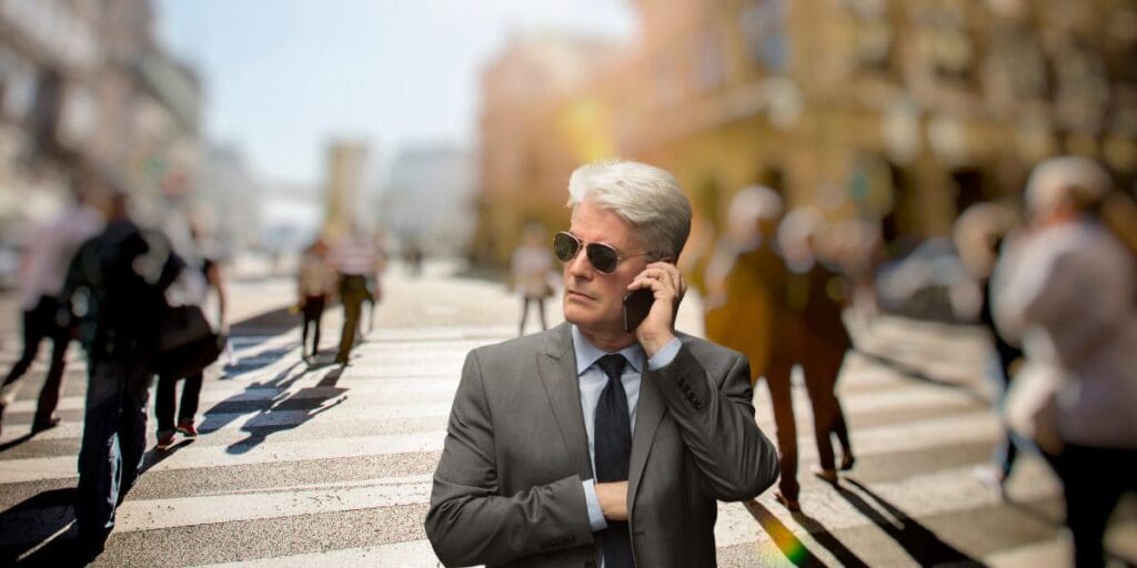 A man in a suit practicing self defense while talking on a cell phone on a busy street.