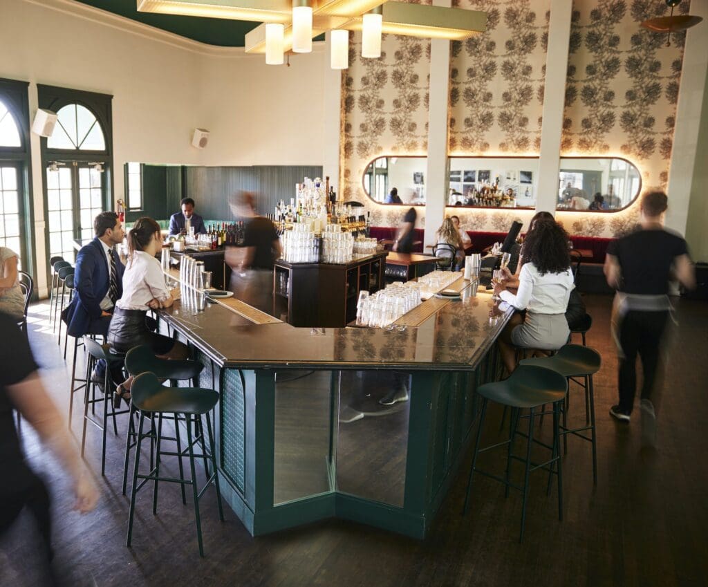 Interior Of Busy Cocktail Bar In Restaurant With Staff Serving Customers