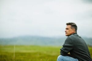 A man sitting alone looking into the distance, deep in thought.