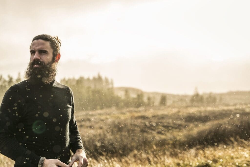 A man standing in sunlit open country in winter.