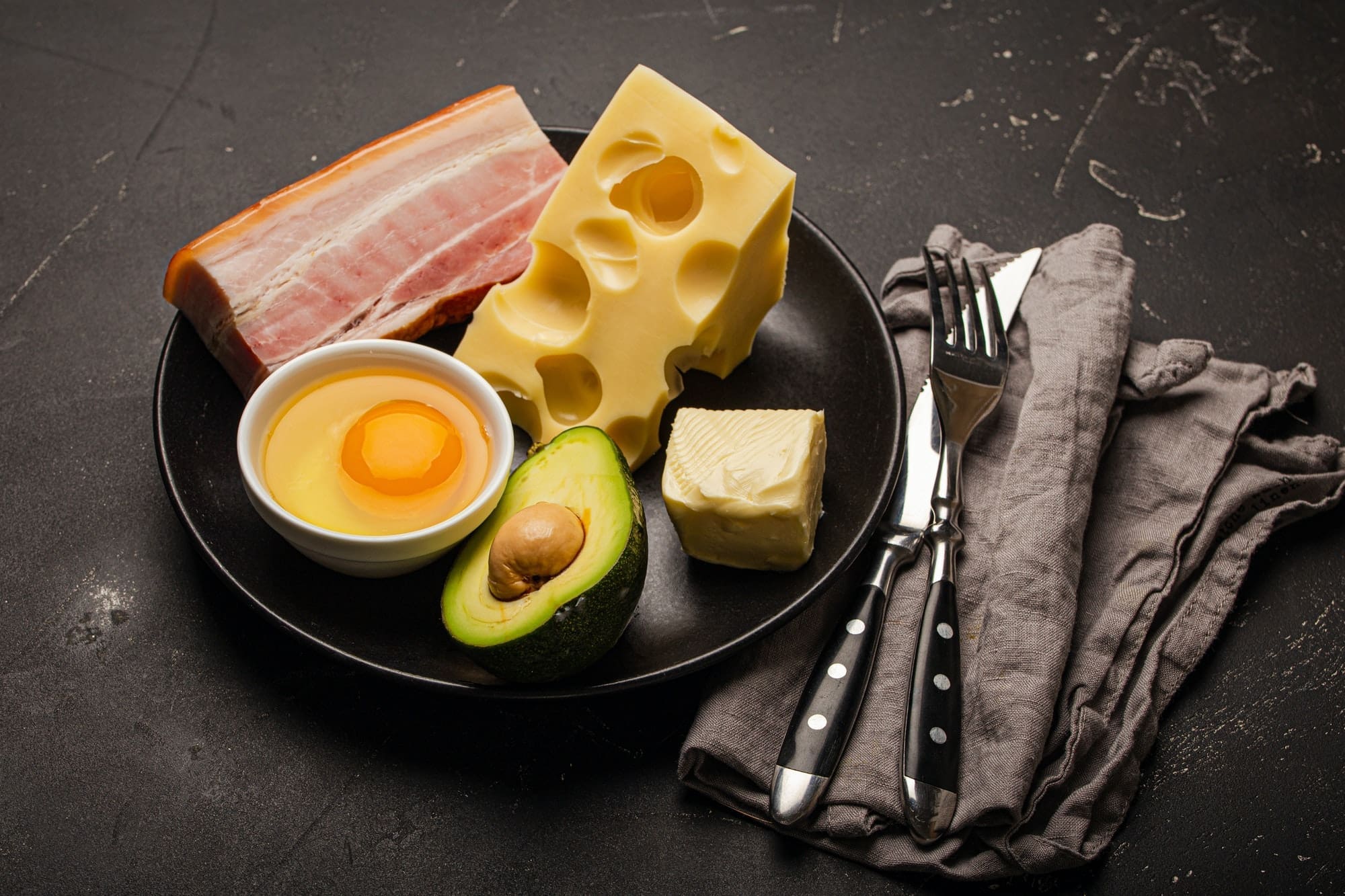 Foods for keto diet on black plate on dark background