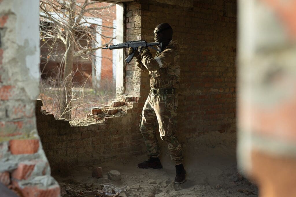 A terrorist during the fighting in an urban area. A ruined brick building.