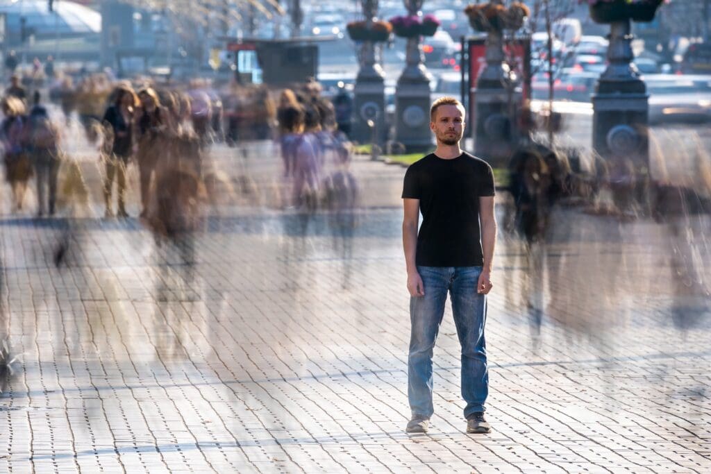 The young man stands in the middle of crowded street.