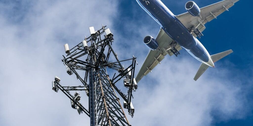 An airplane is flying over a cell tower.