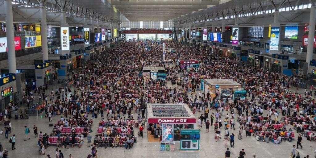 A bustling train station filled with crowds of passengers during peak travel hours, all exercising situational awareness.