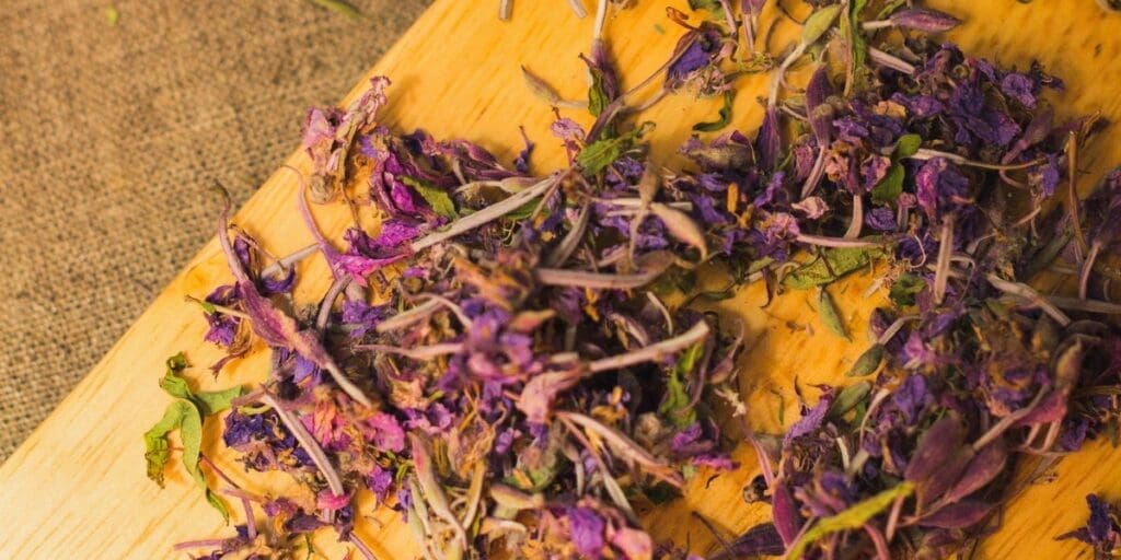 Dried fireweed flowers scattered on a wooden surface.