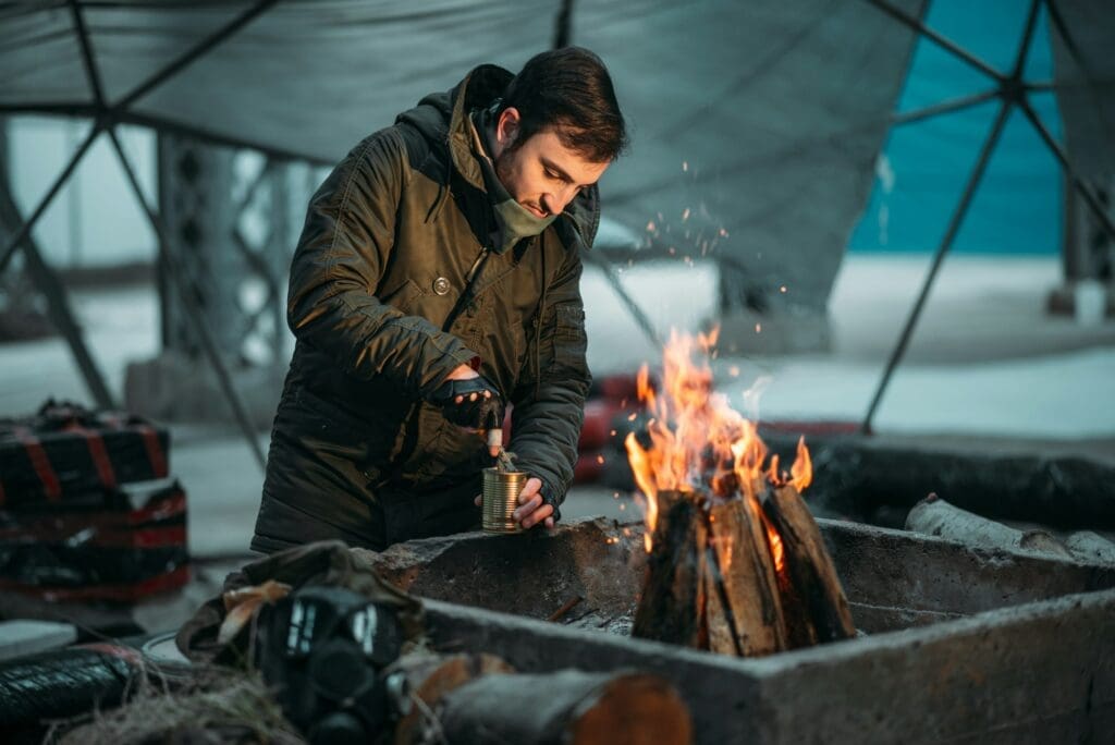 Prepper opening a can of food by open fire. 