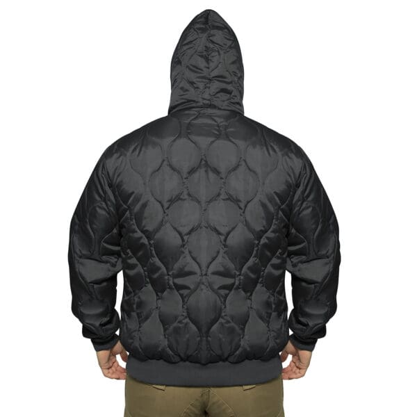 Person facing away, wearing the Rothco Quilted Woobie in a dark quilted hooded sweatshirt style paired with khaki pants against a white background.