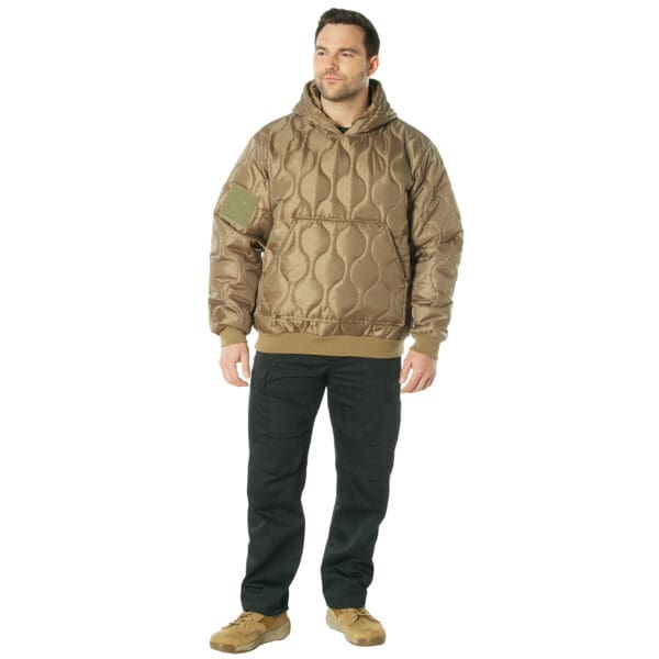 A man wearing a Rothco brown quilted woobie hooded sweatshirt with black 2XL cargo pants and tan boots stands against a white background.