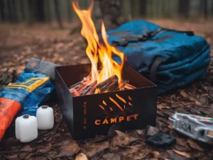 The portable metal fire pit labeled "CAMPET" crackles with burning logs, a must-have for any adventurer. It sits on the forest floor, surrounded by a blue backpack, two white containers, and a colorful bag—perfect companions for your bugout bags and firestarter essentials.